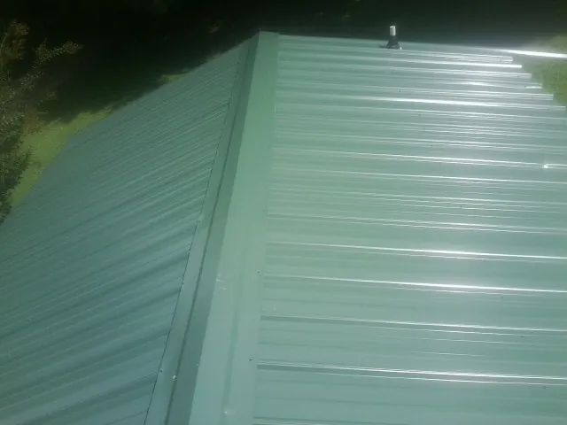 New green metal panels meeting at the ridge of a roof — Flat Roof Repair work by our crew in Eagle Springs
