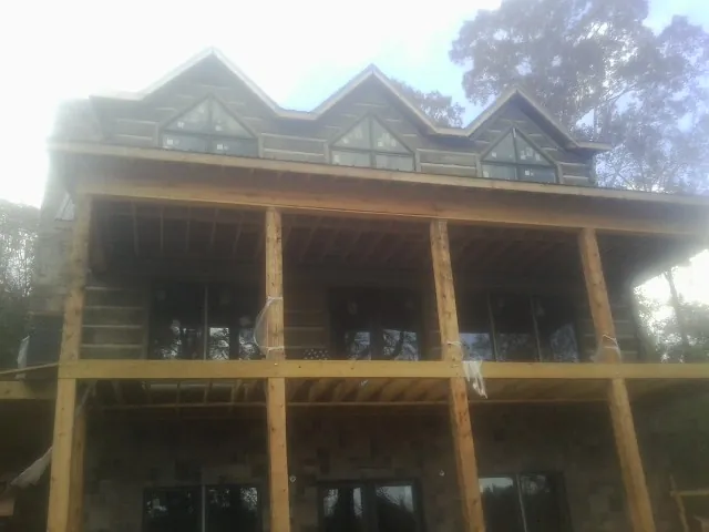 Dormers and porch framing on a large log home under construction — Roof Coating work by our crew in Eagle Springs