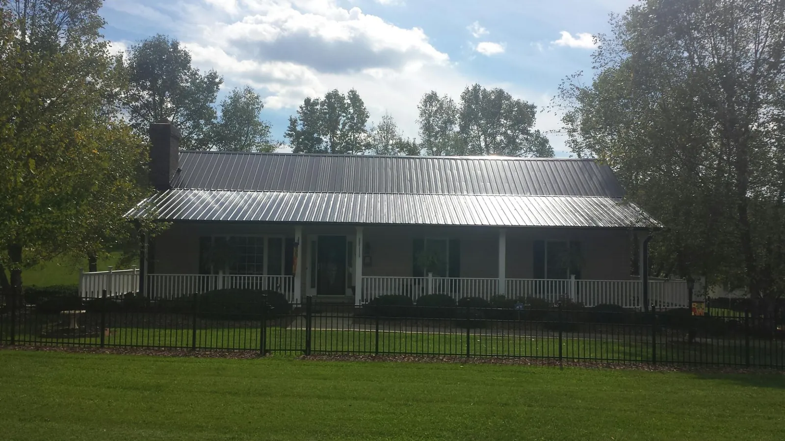 Gray metal roof on a brick ranch with a full width front porch — Gutter Guard Installation work by our crew in Eagle Springs