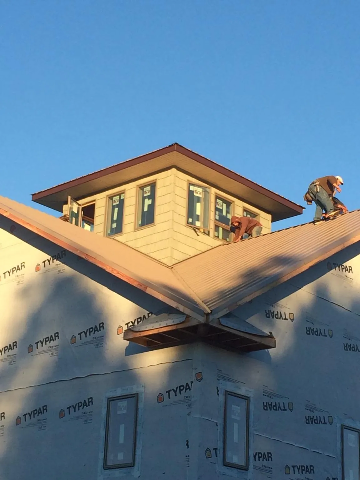 Roofers working around a rooftop cupola on a new metal roof at sunset — Roof Waterproofing in Eagle Springs by Roofing Brothers